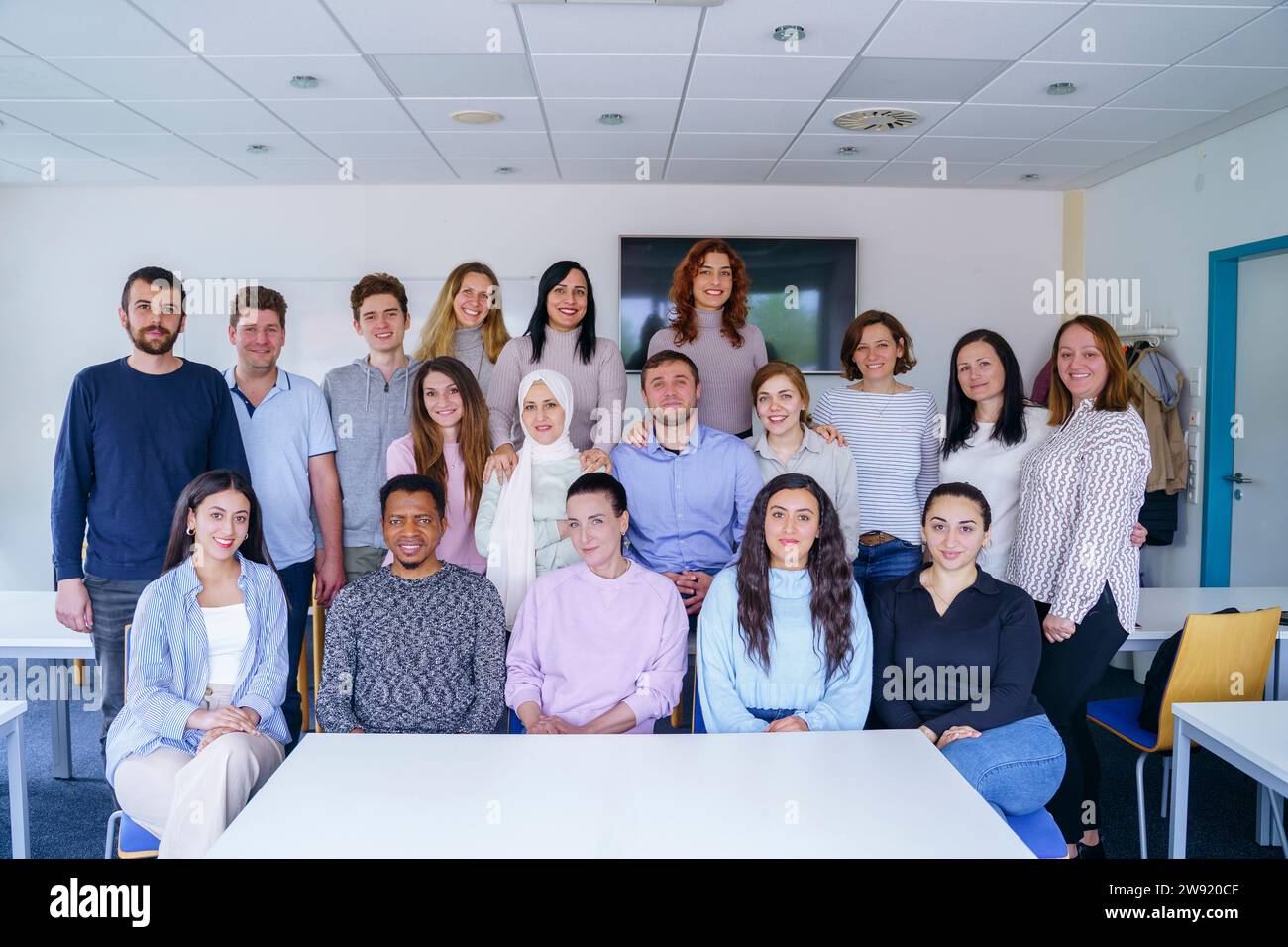 Smiling multi-ethnic students together in classroom Stock Photo