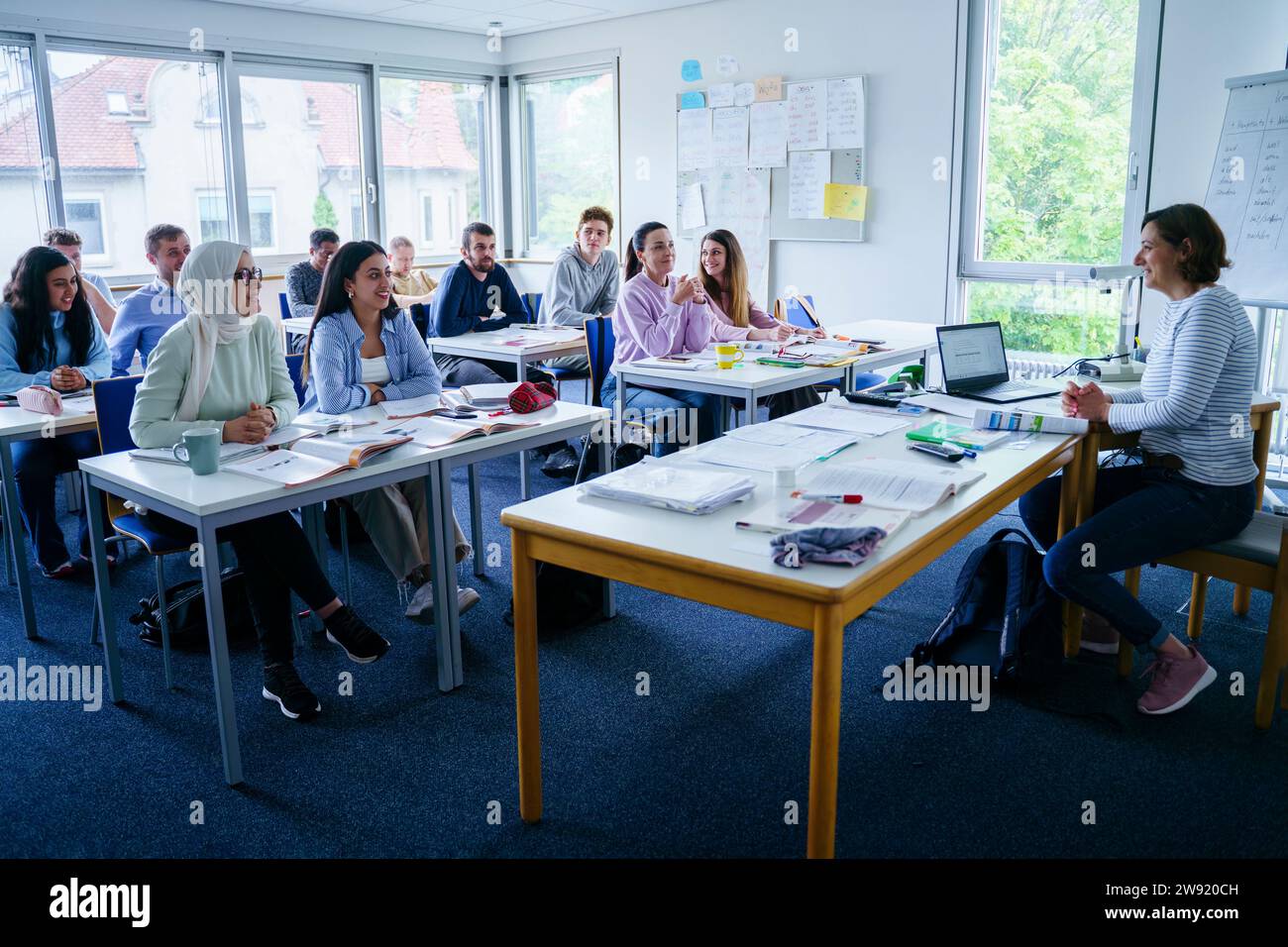 Smiling teacher teaching to multi-ethnic students in classroom Stock Photo