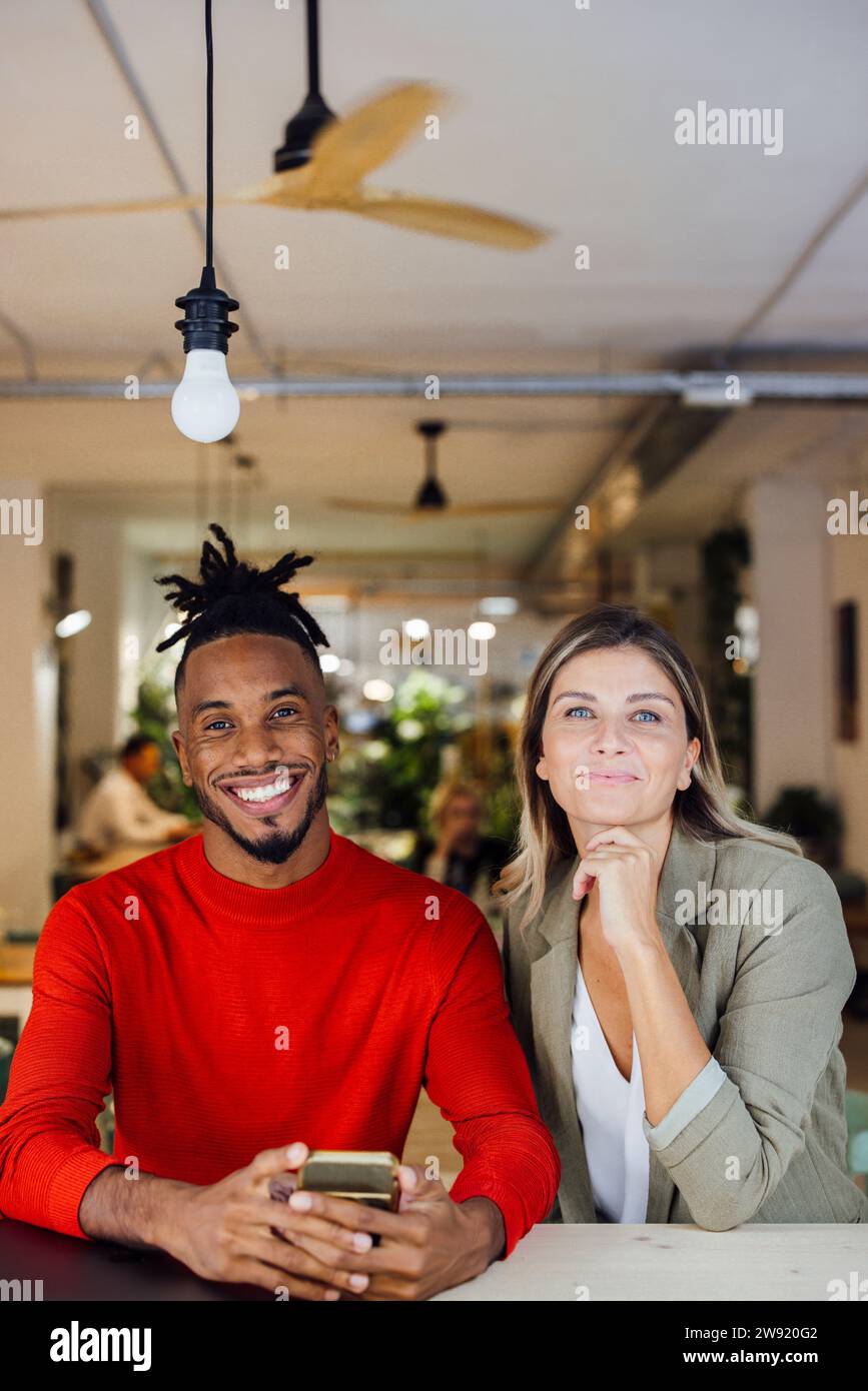 Smiling multiracial business colleagues sitting at cafe Stock Photo