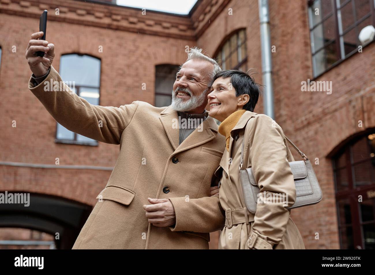 Happy elderly couple taking selfie on smartphone during city walk Stock Photo