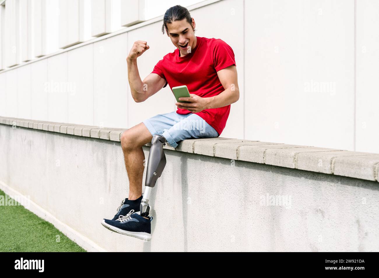 Happy man with disability flexing muscles and using smart phone Stock Photo