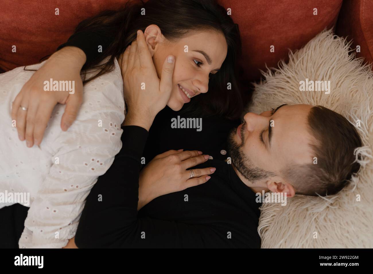 Young man lying down and embracing woman at home Stock Photo