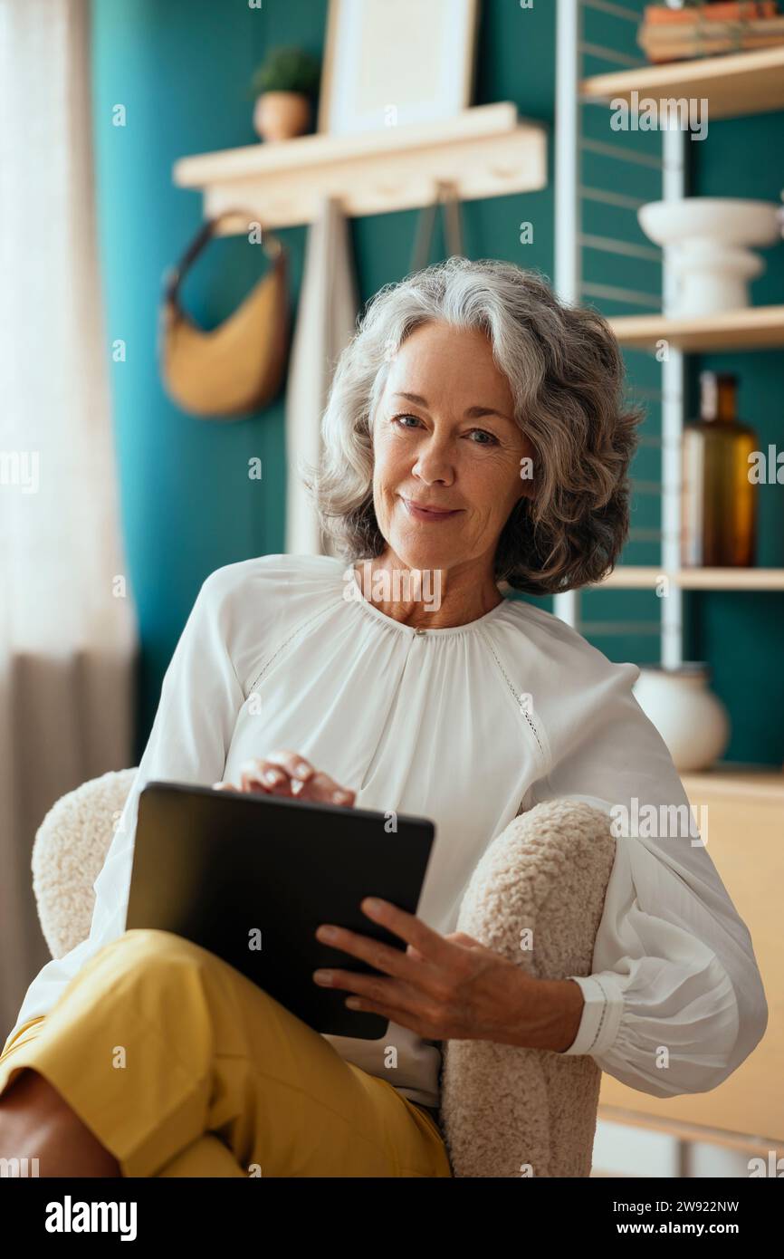 Smiling psychologist with tablet PC sitting at home Stock Photo