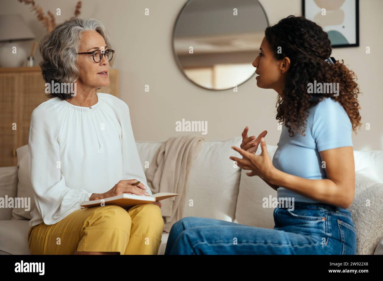 Woman talking to psychologist on sofa at home Stock Photo