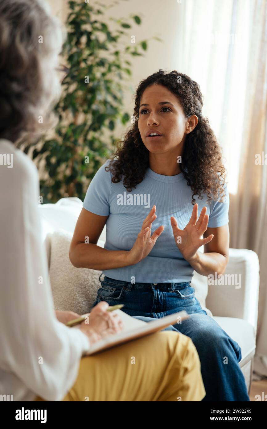 Patient talking about mental health issues with psychotherapist at home Stock Photo