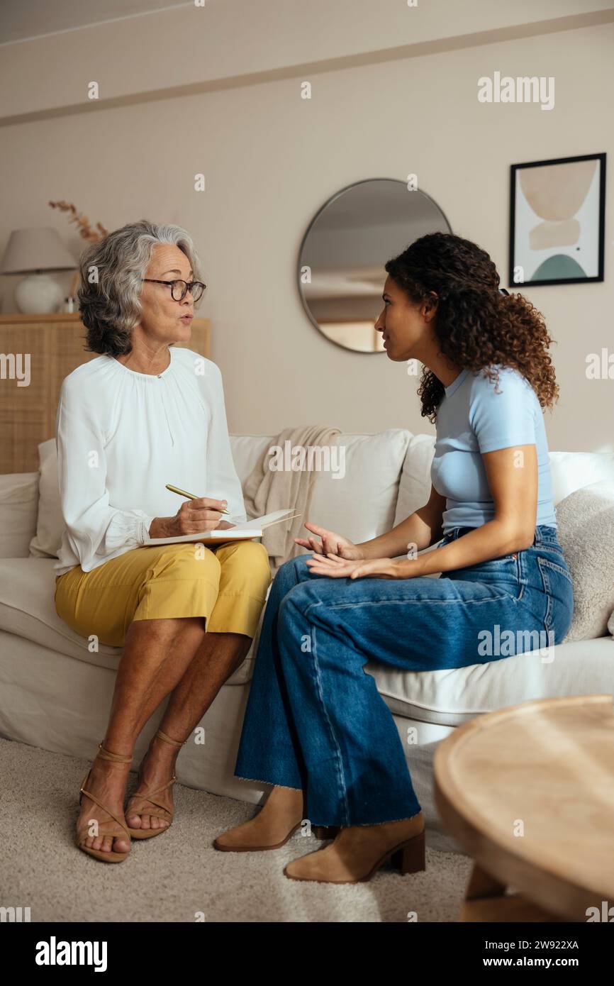 Psychotherapist talking with patient sitting in living room at home Stock Photo