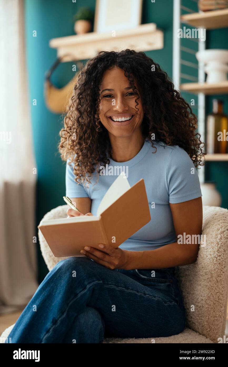Happy psychotherapist sitting with diary at home Stock Photo