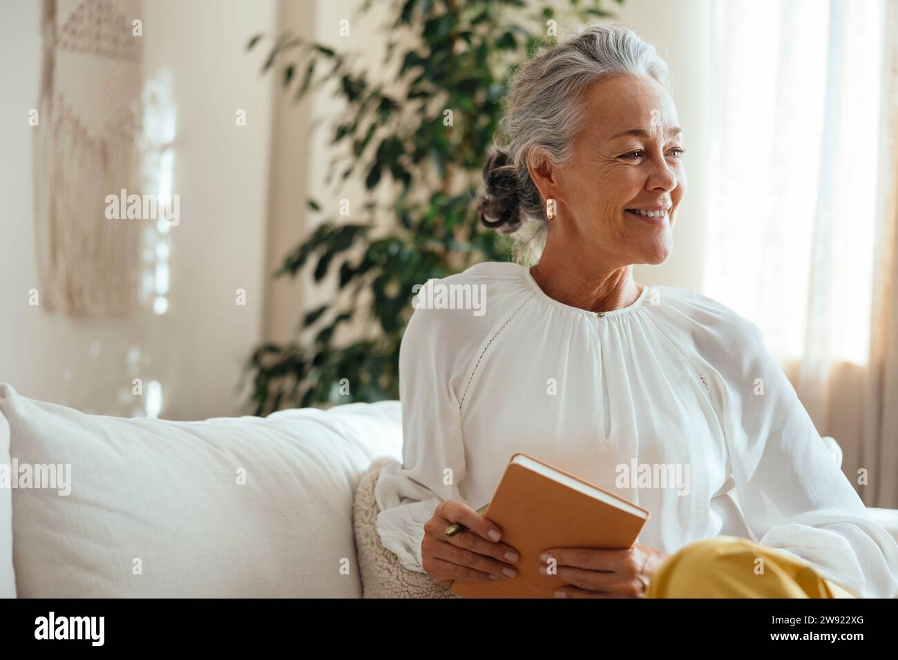 Smiling psychologist holding diary and sitting at home Stock Photo