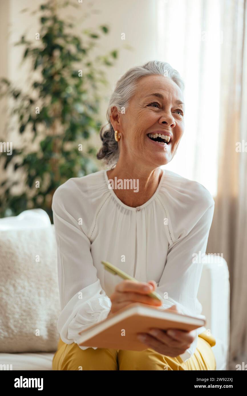 Happy psychologist holding diary and sitting at home Stock Photo