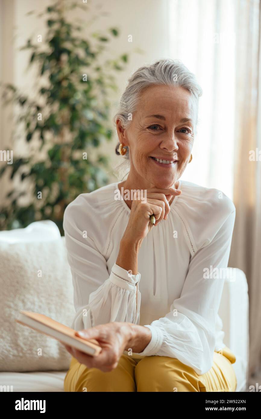 Smiling therapist with hand on chin sitting at home Stock Photo
