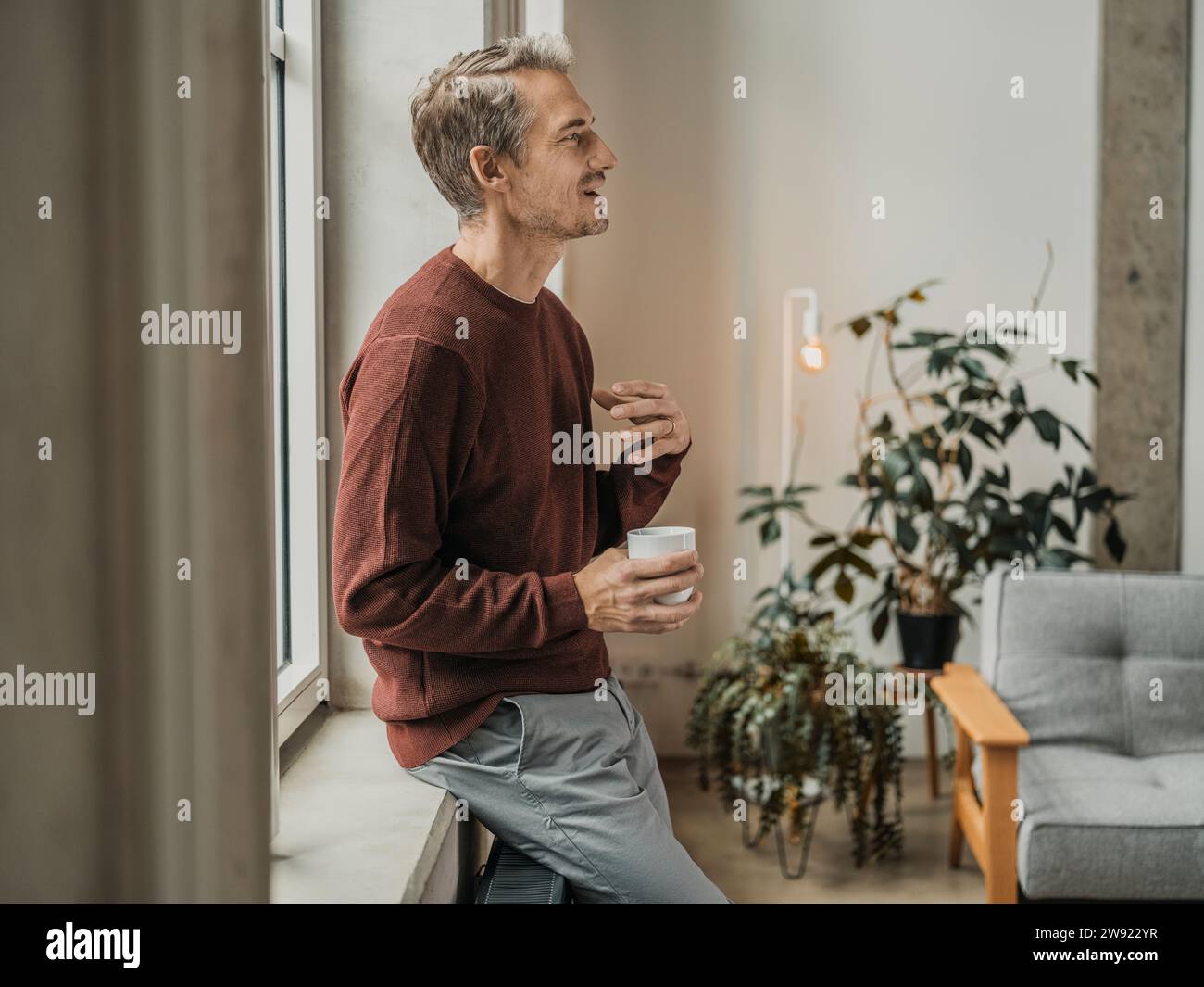 Man holding coffee cup and gesturing at home Stock Photo