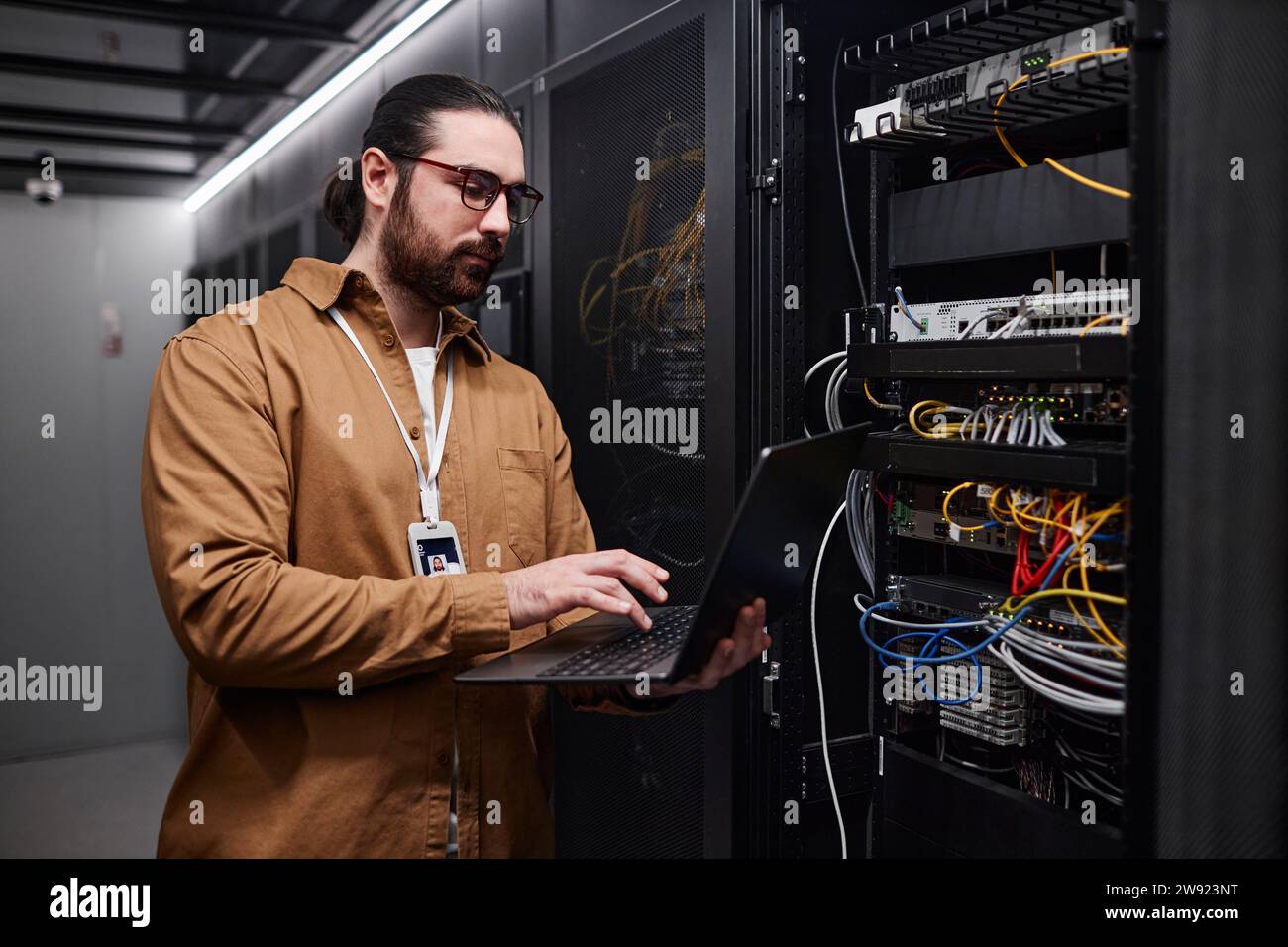 Young IT engineer using laptop and setting computer network in data room Stock Photo