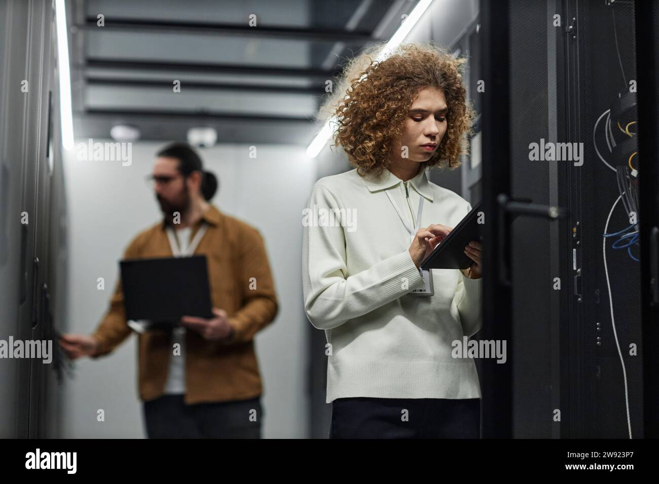 IT engineer using tablet PC with colleague working in background Stock Photo