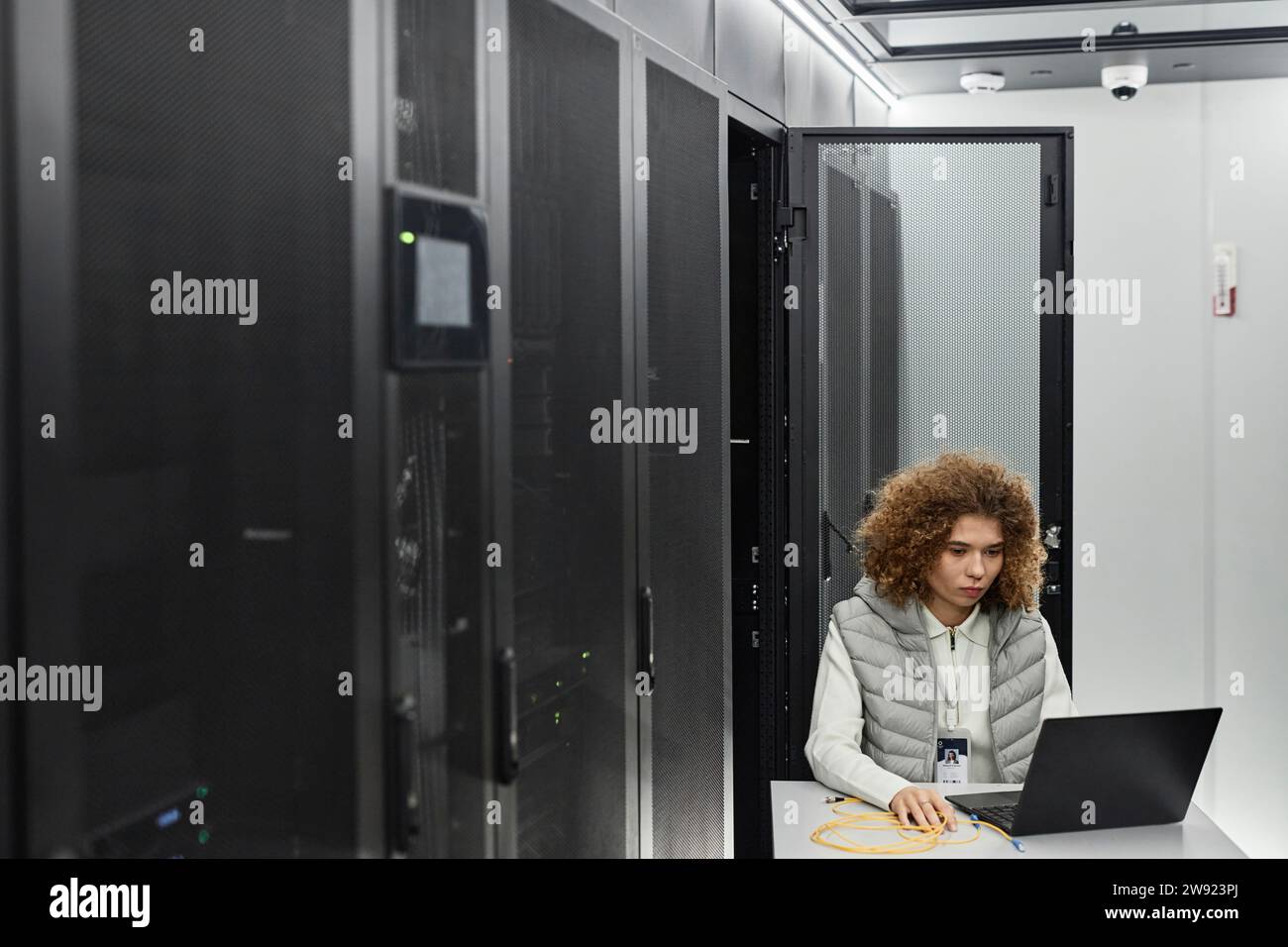 Engineer working on laptop and sitting in server room Stock Photo