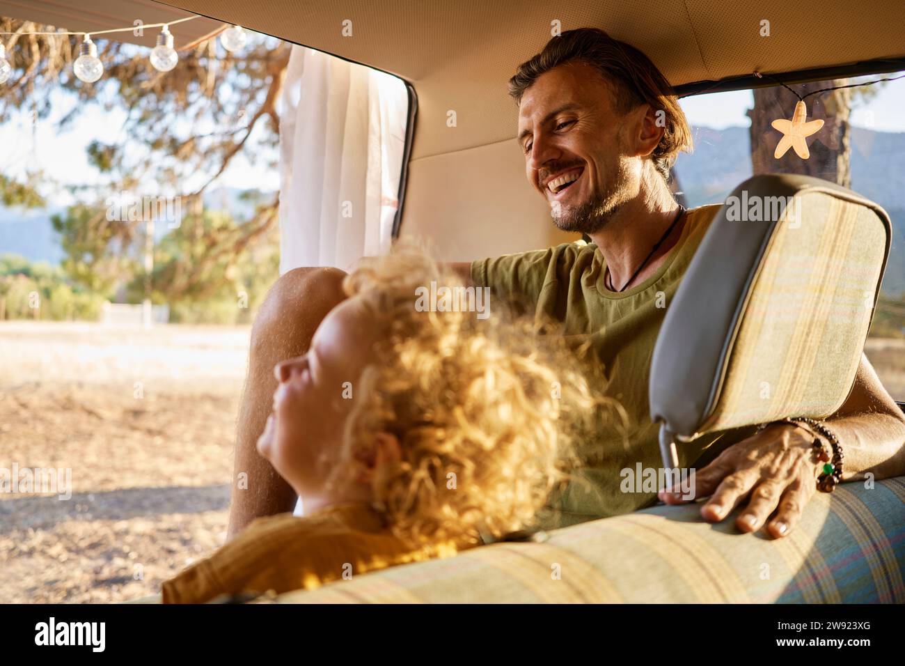 Father laughing with daughter and spending leisure time in caravan Stock Photo