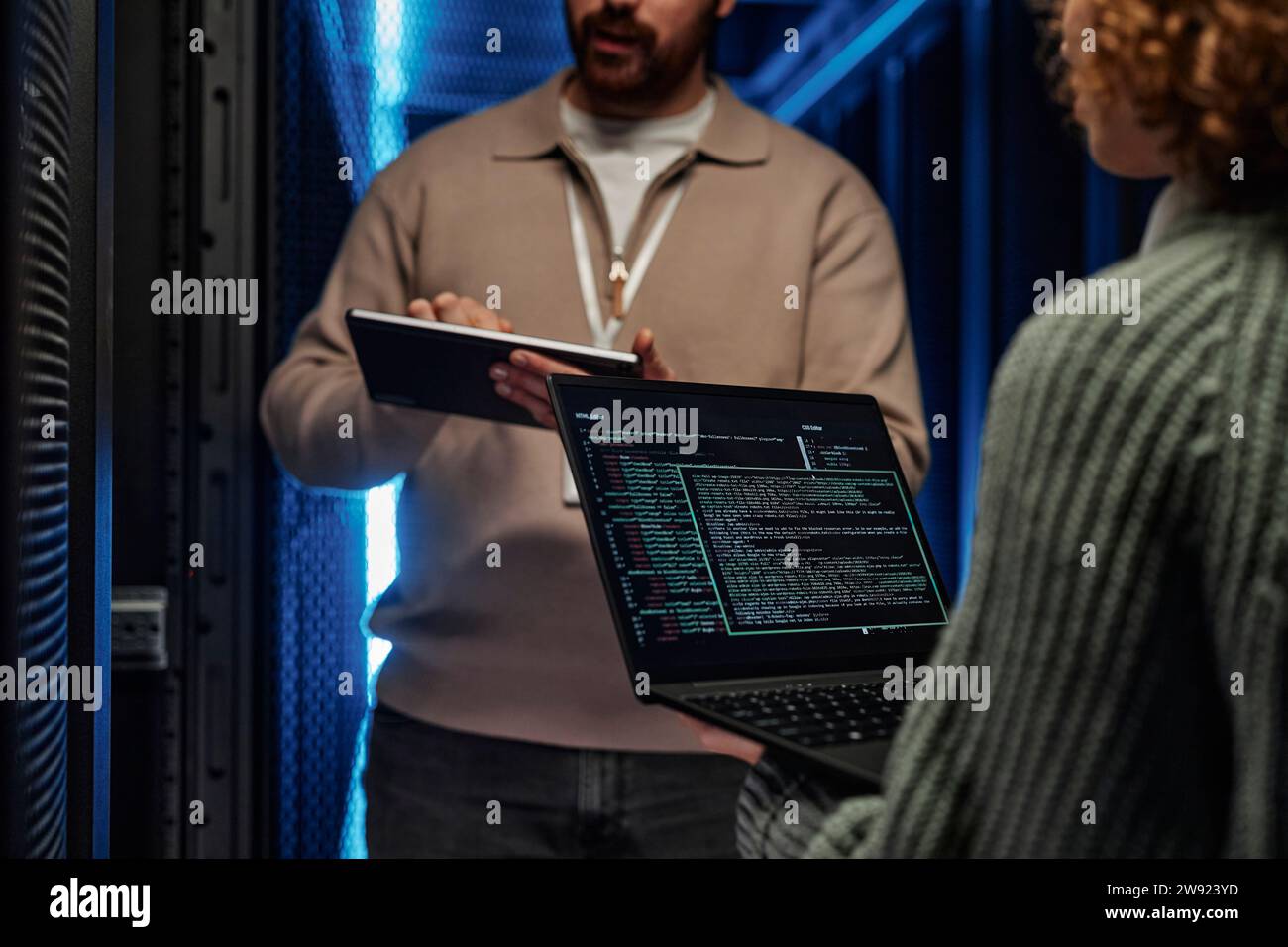 IT professionals working and discussing over data on laptop in server room Stock Photo