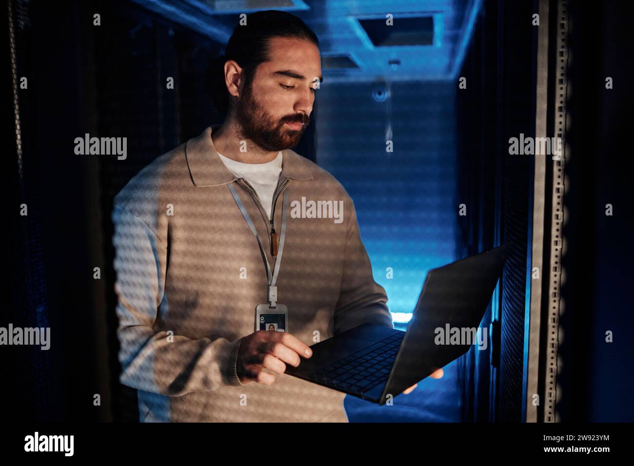 Young IT professional using laptop and working in data center Stock Photo