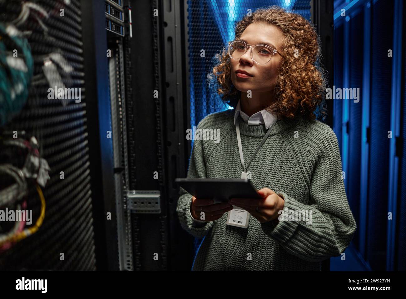 Young IT engineer examining supercomputer equipment and holding tablet PC in data center Stock Photo