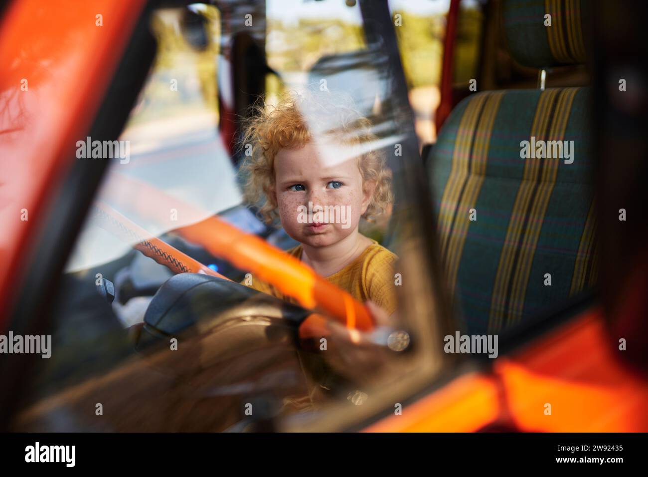 Innocent girl sitting on driver's seat of motor home Stock Photo