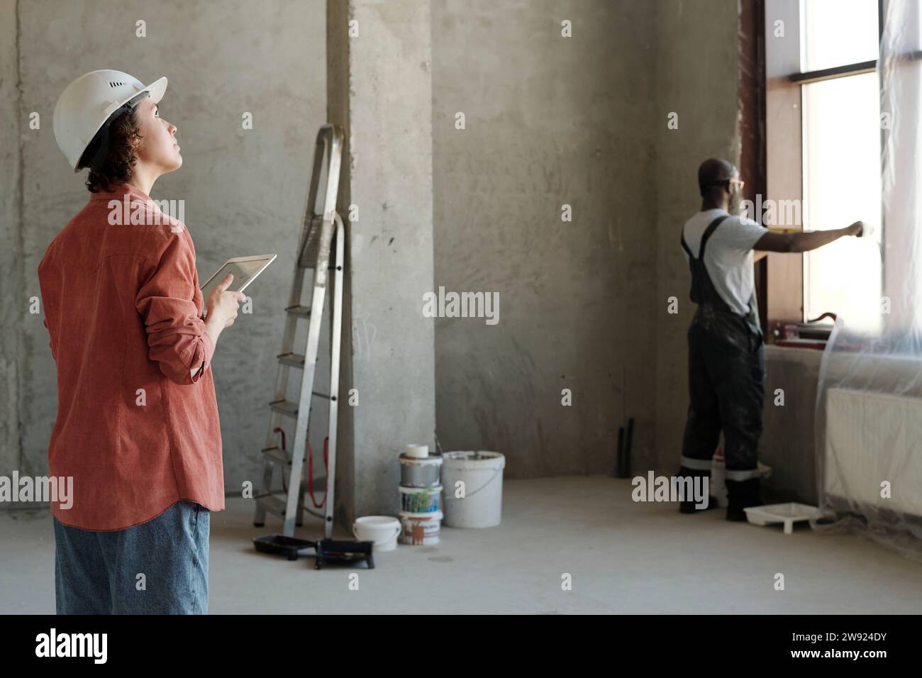 Engineer holding tablet PC with coworker looking through window at construction site Stock Photo