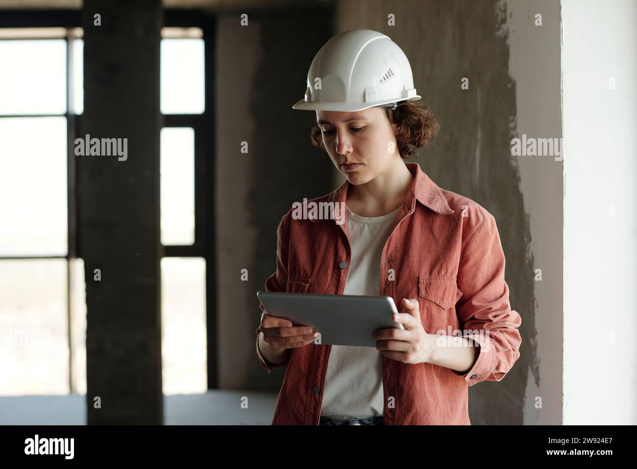 Engineer wearing hardhat and using tablet PC at construction site Stock Photo