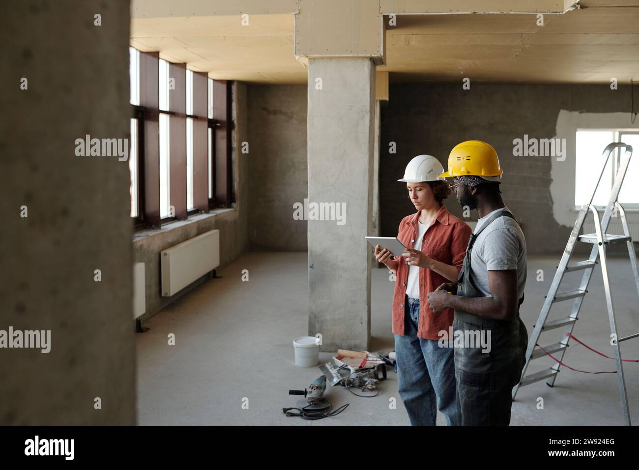 Engineer using tablet PC and planning with coworker at construction site Stock Photo