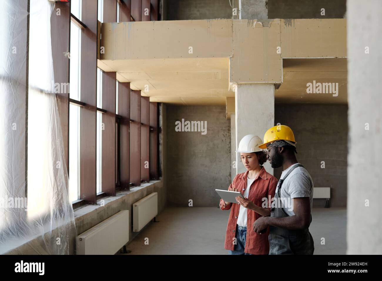 Engineer using tablet PC and discussing with coworker at construction site Stock Photo