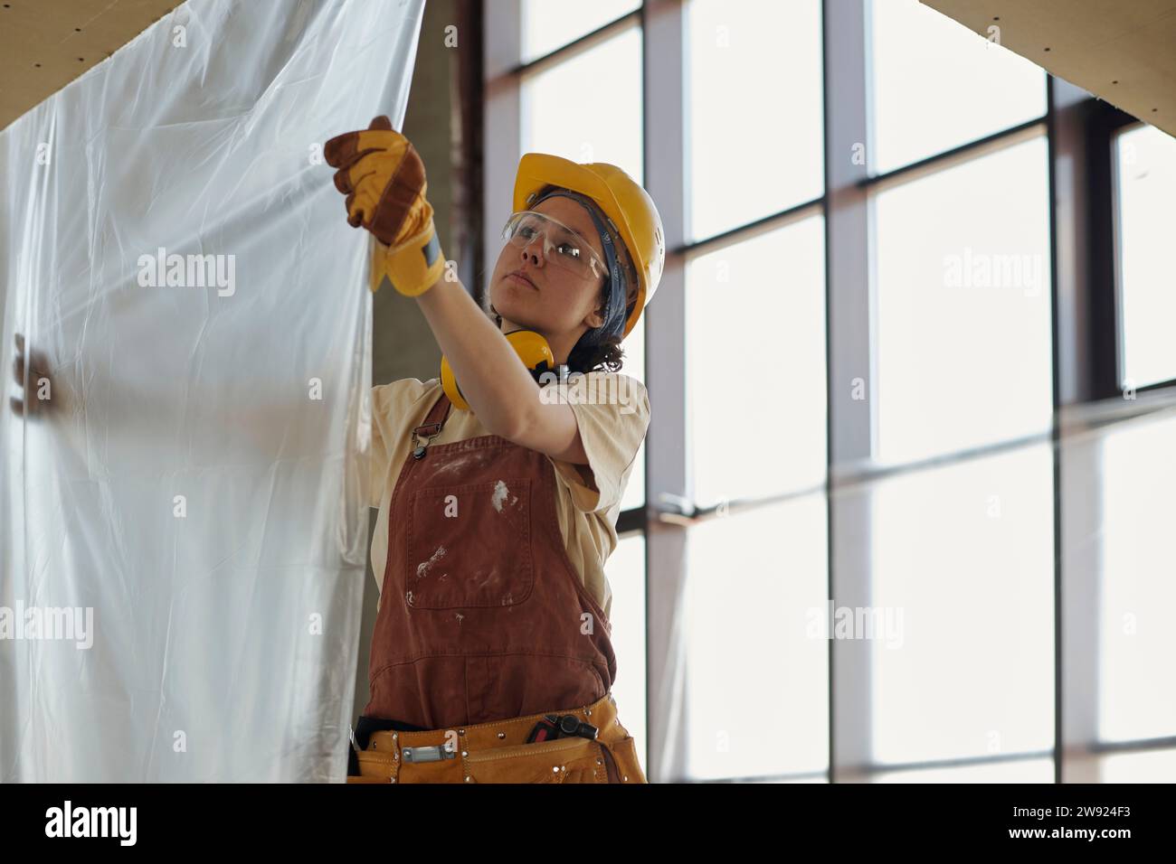 Young construction worker hanging plastic foil at site Stock Photo Alamy
