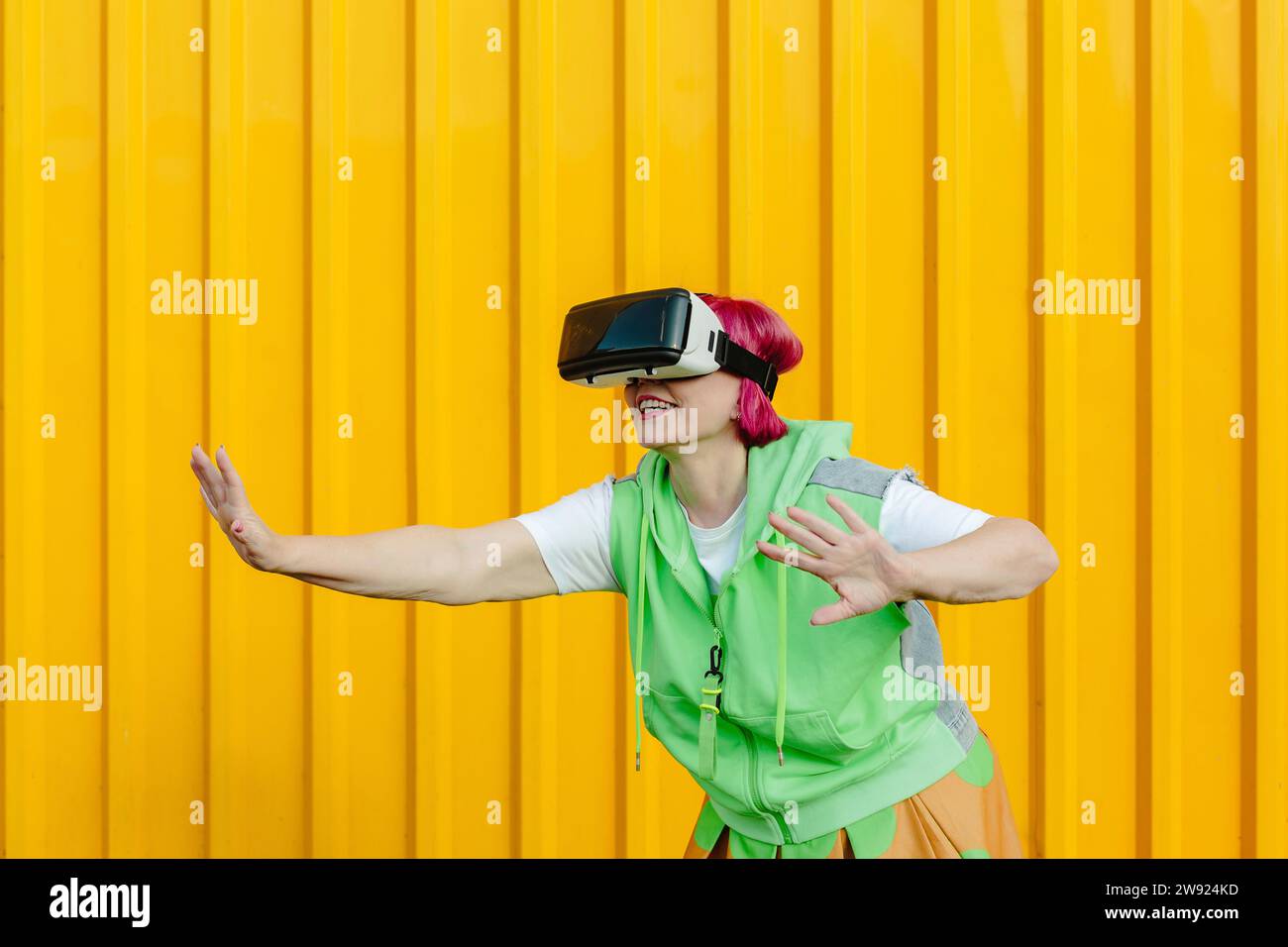 Senior woman wearing virtual reality simulator and gesturing in front ...