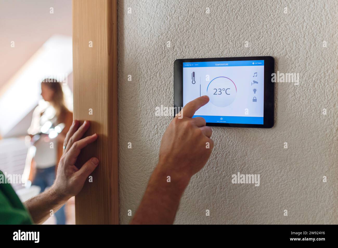 Man adjusting temperature through home automation app on tablet PC Stock Photo