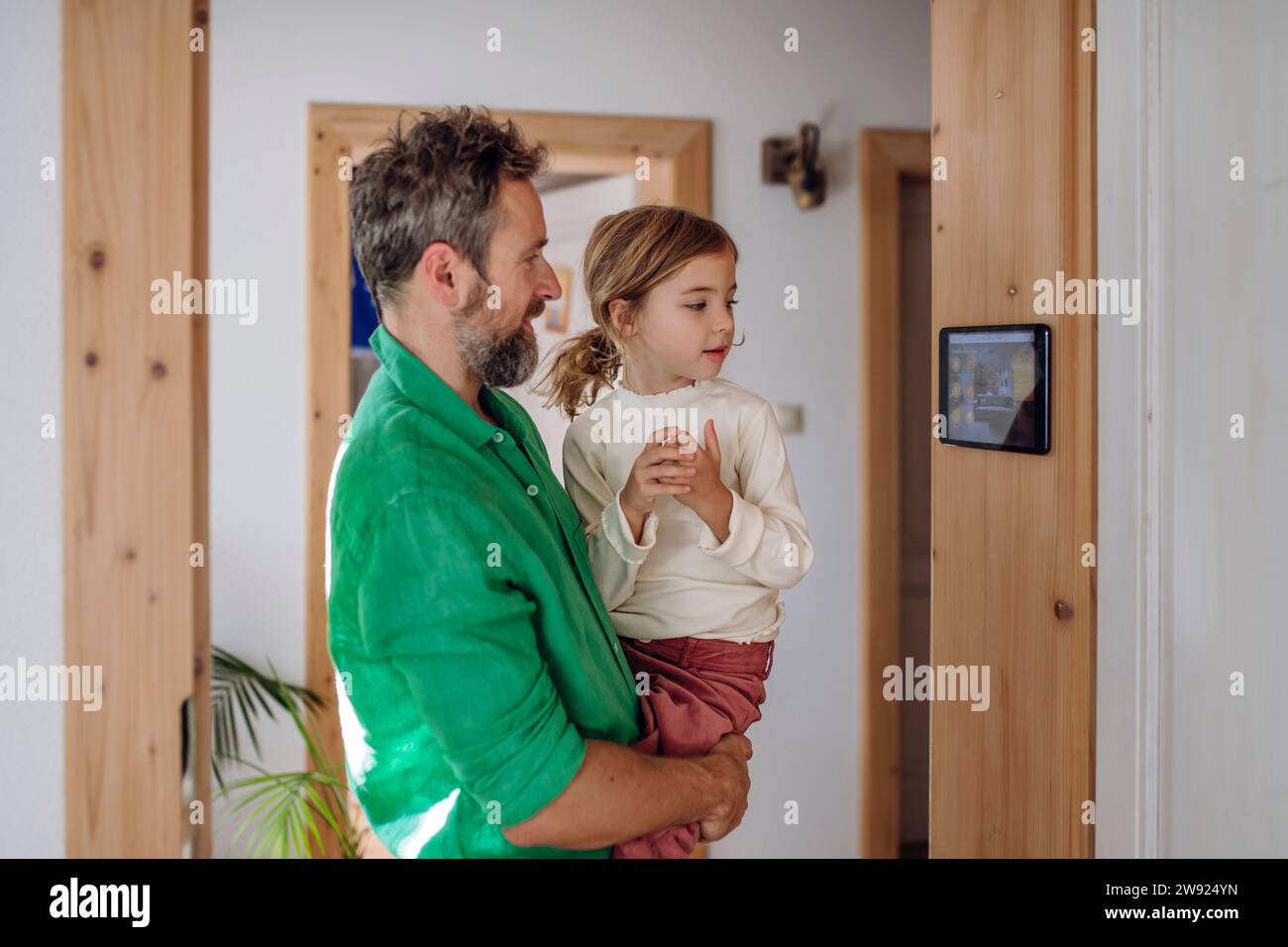 Daughter looking at home automation app on tablet PC with father Stock Photo