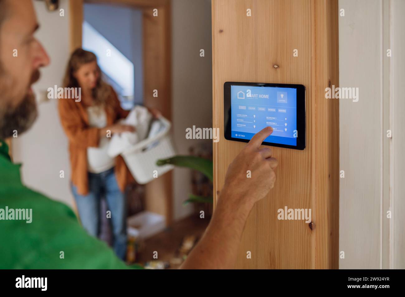 Man adjusting temperature through app on tablet PC at home Stock Photo
