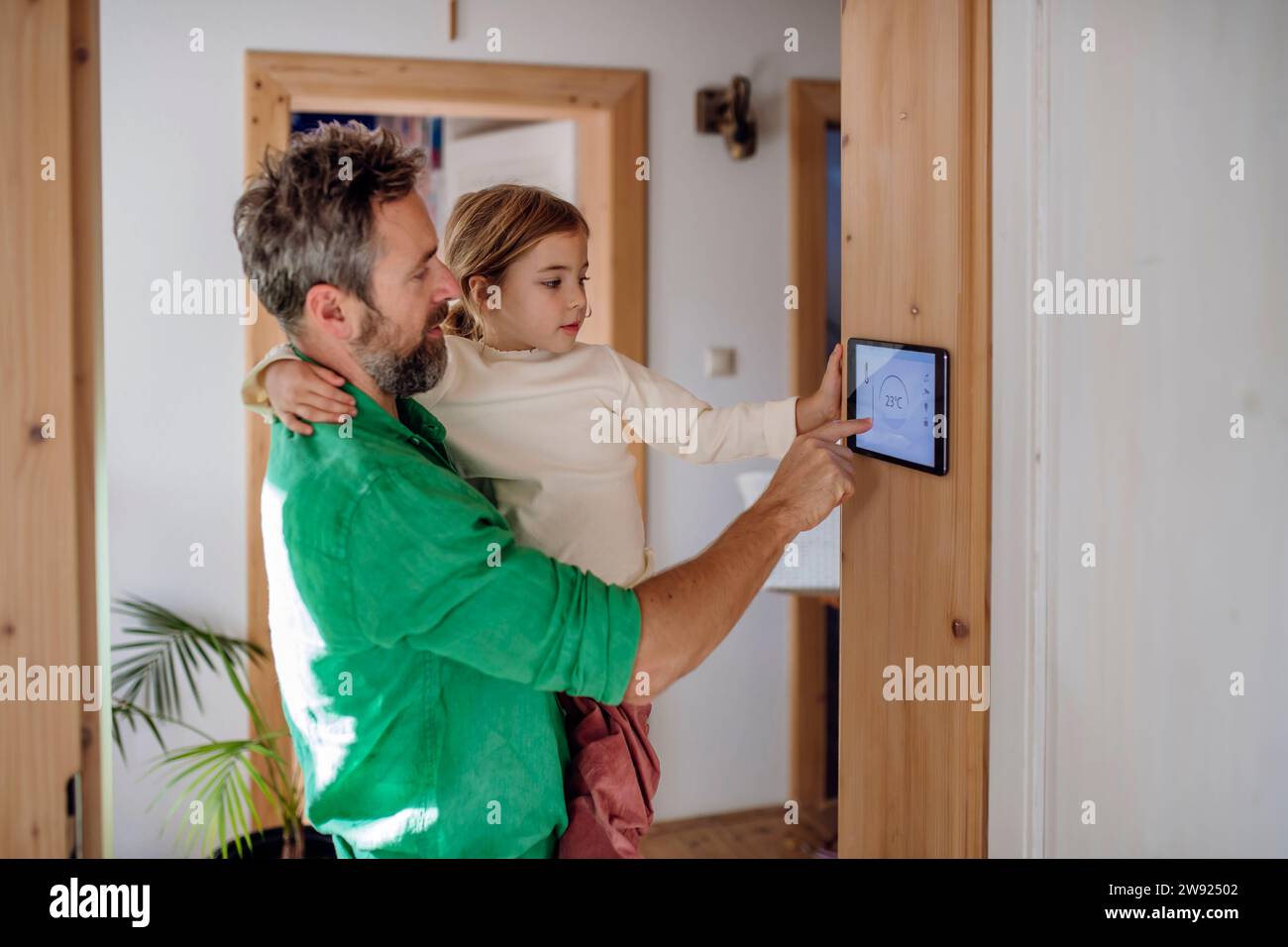 Father teaching daughter to adjust home automation app on tablet PC Stock Photo