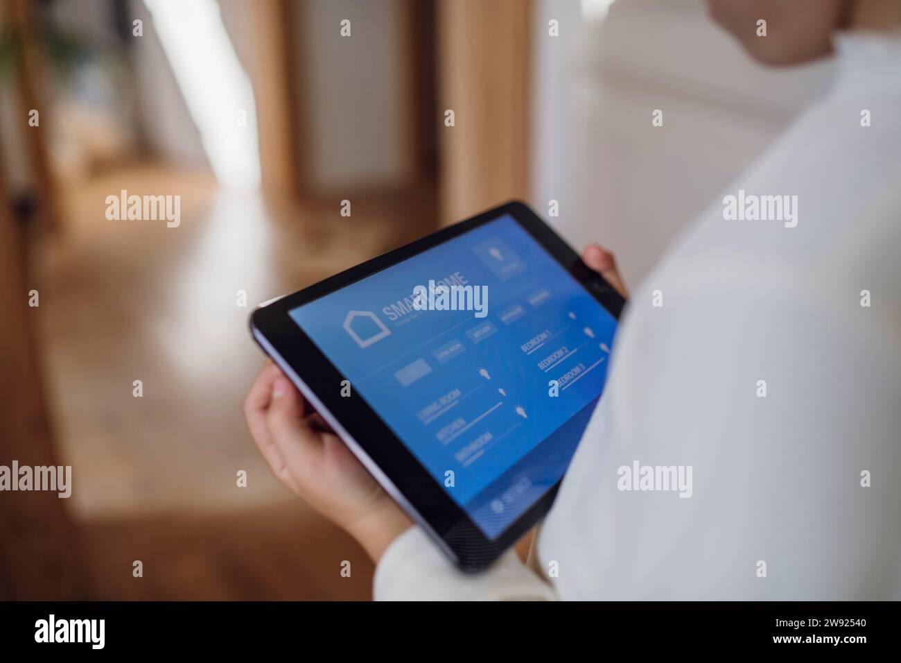 Girl adjusting temperature through home automation app on tablet PC Stock Photo