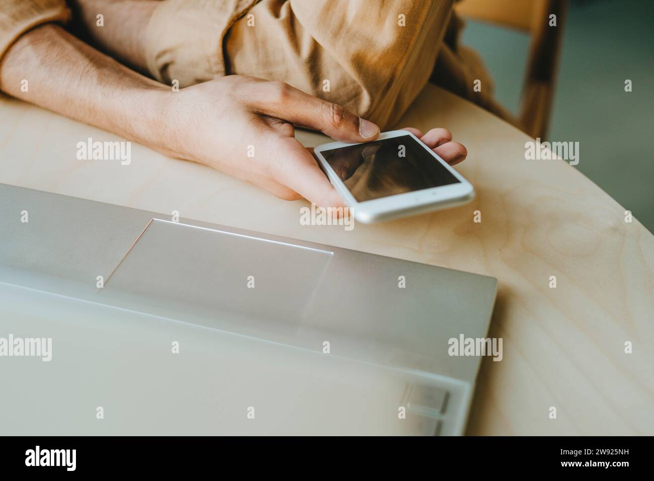 Young man text messaging through phone on table at home Stock Photo