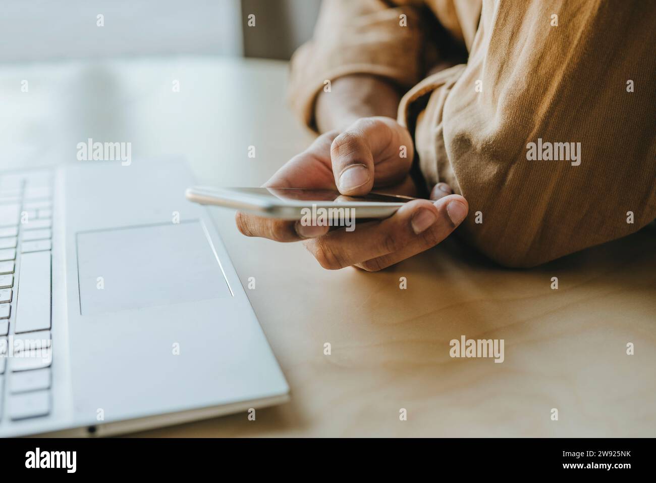 Young man text messaging through mobile phone on table at home Stock Photo