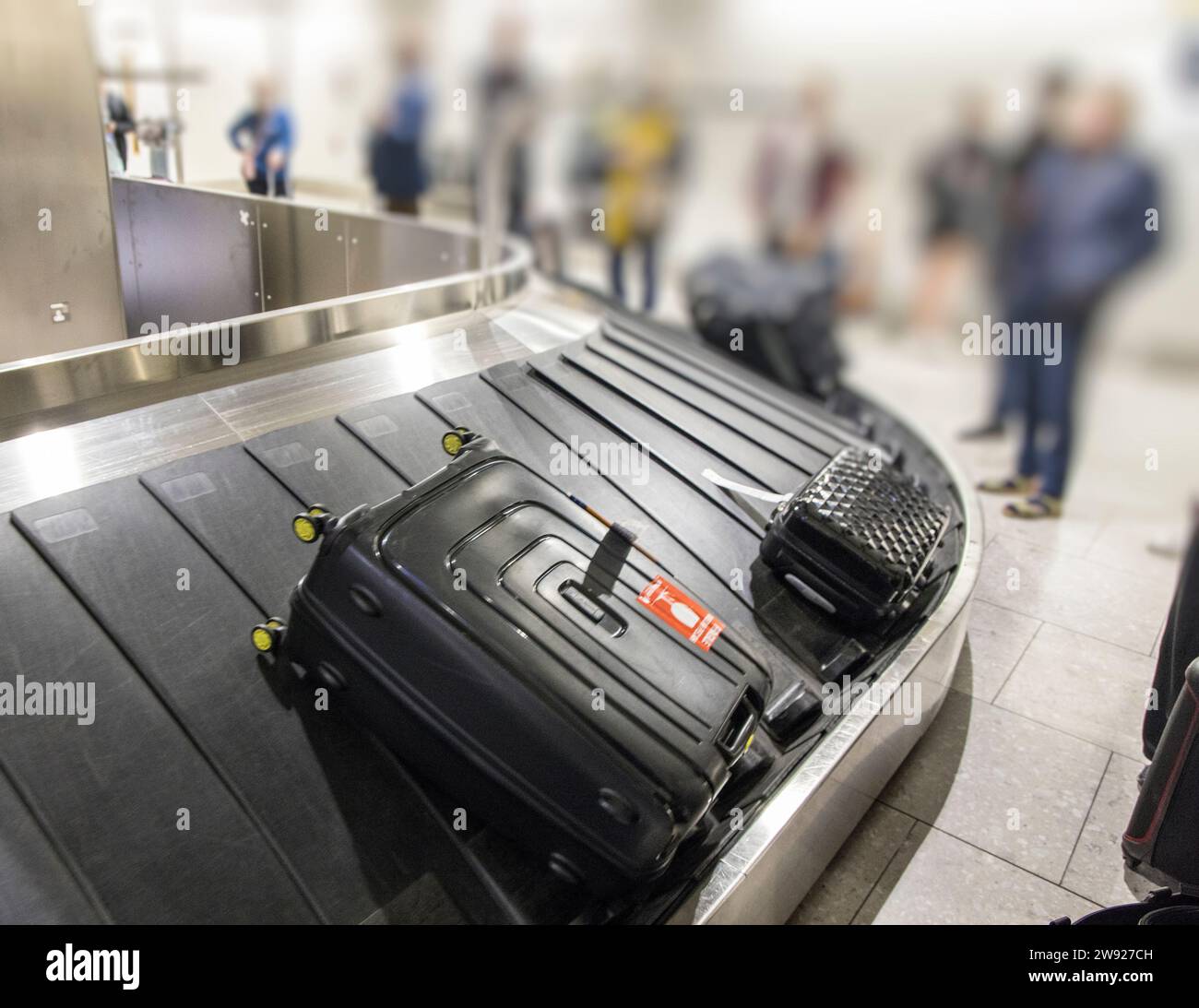 Luggage on airport baggage reclaim with passengers waiting to collect