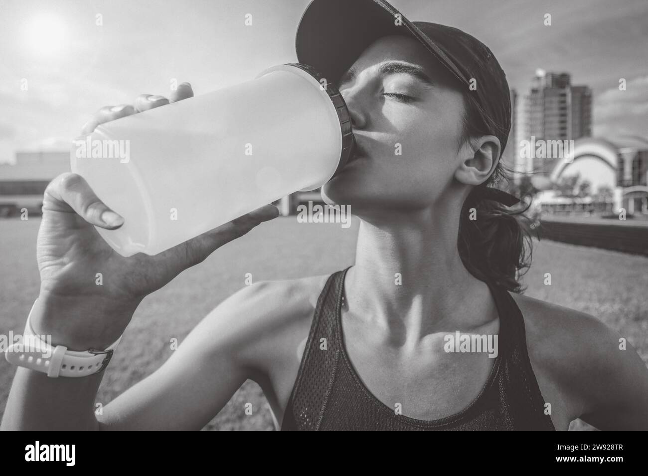 Image of a girl drinking from a bottle after a run. Running concept. Mixed media Stock Photo