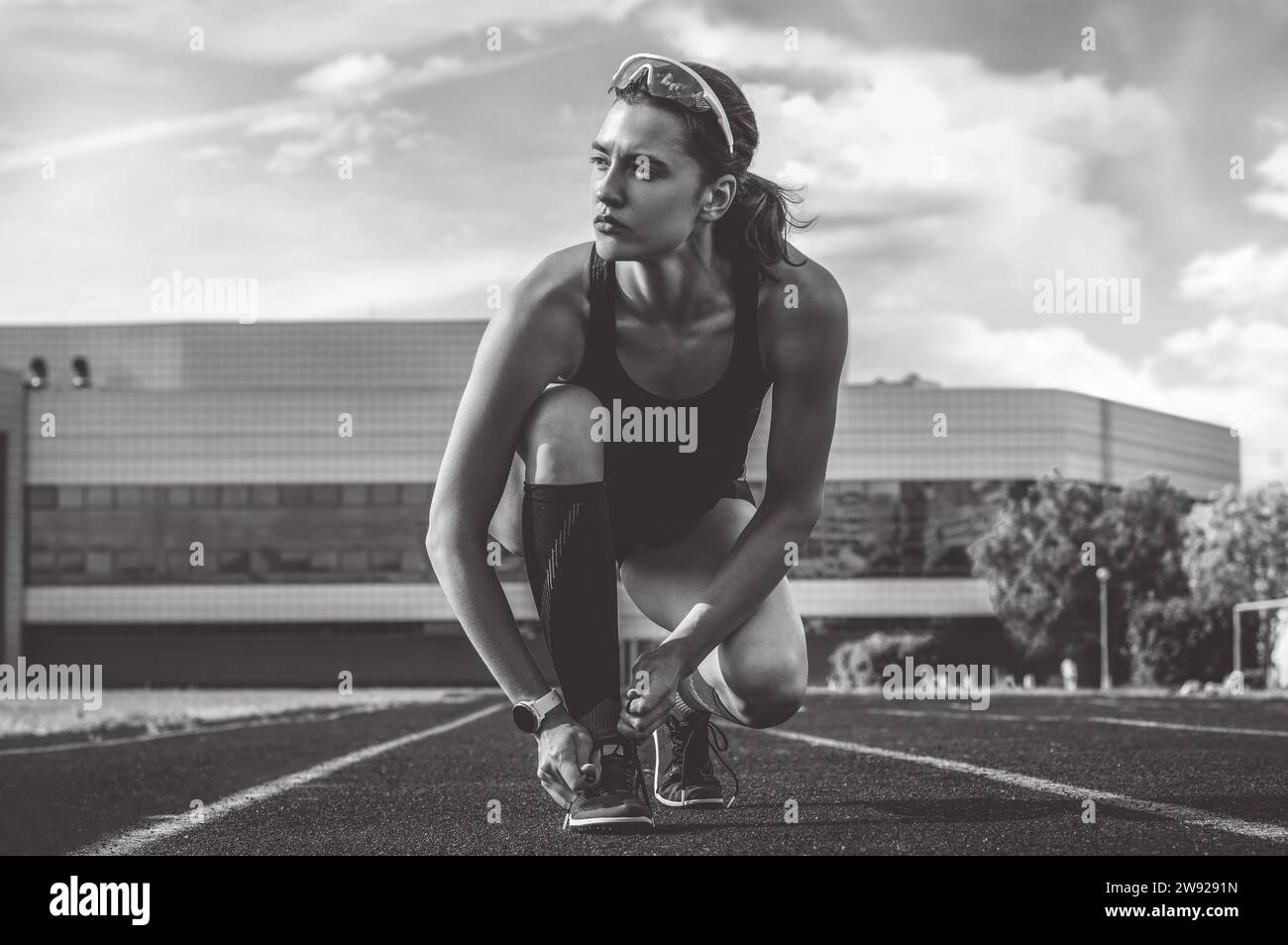 Image of an athlete tying her shoelaces with spikes. Running concept. Mixed media Stock Photo