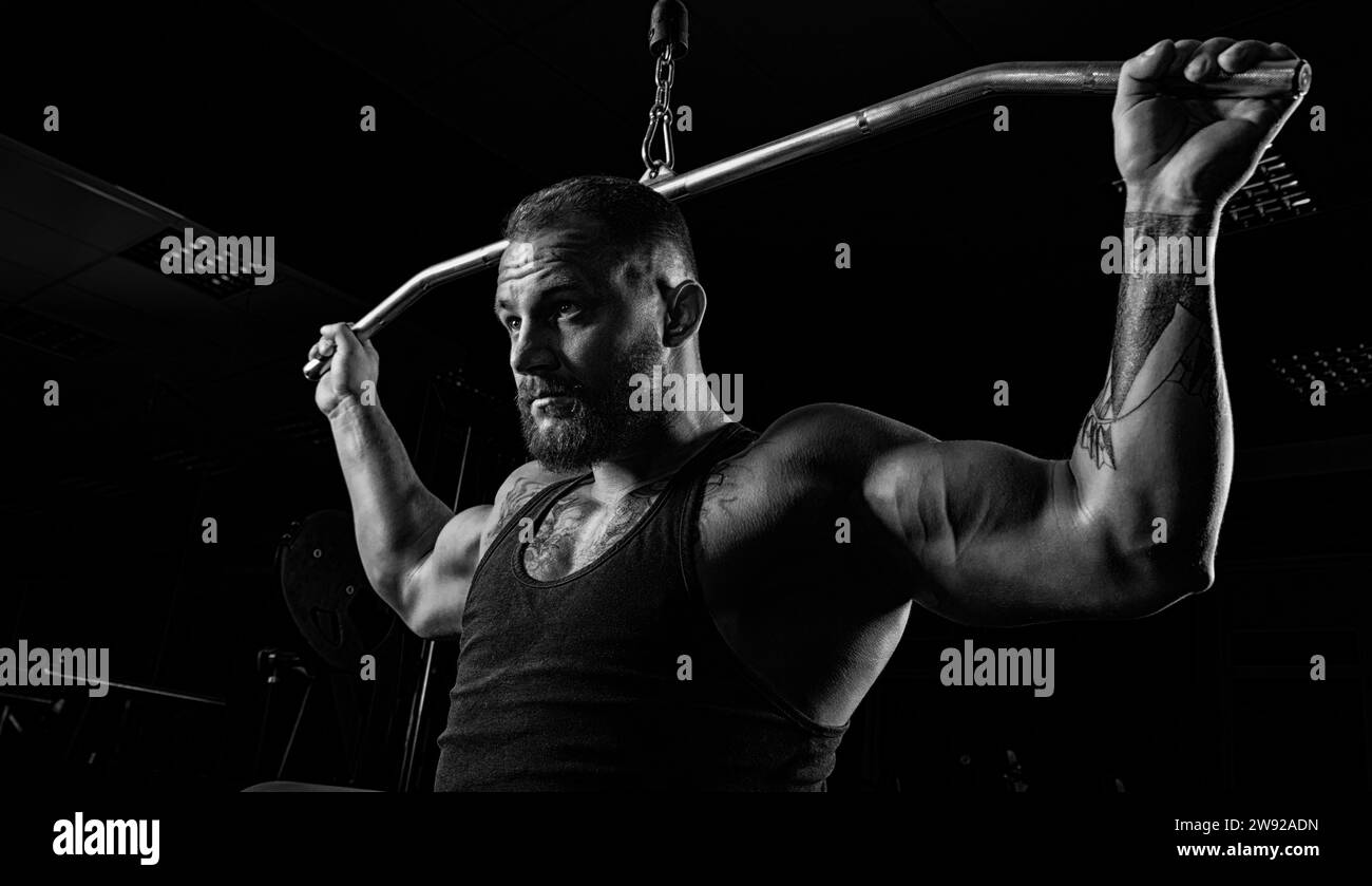 Professional athlete performs an exercise in the gym. Pulls the bar to