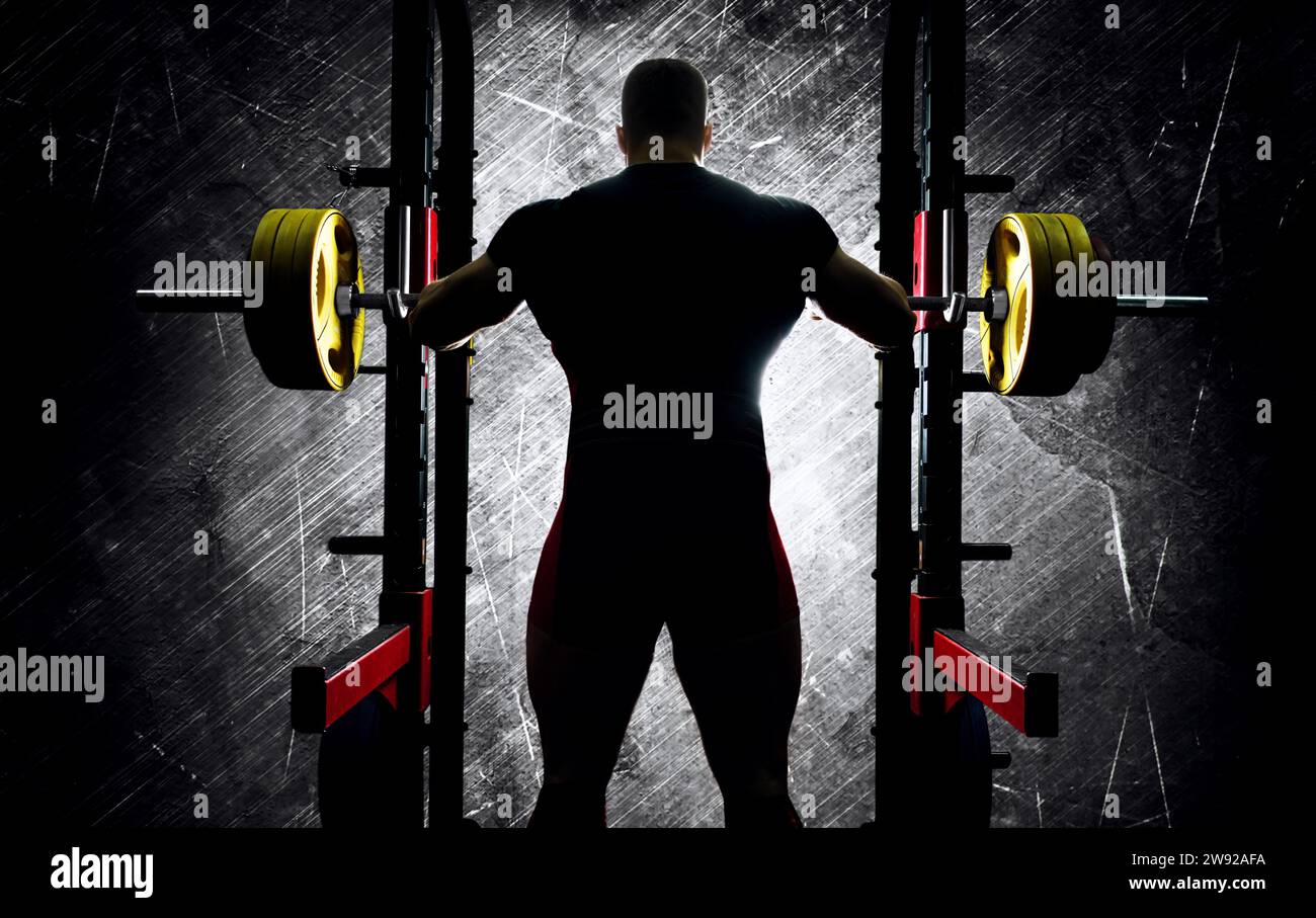 The weightlifter stands with his hands behind the heavy barbell. Back view Stock Photo Alamy