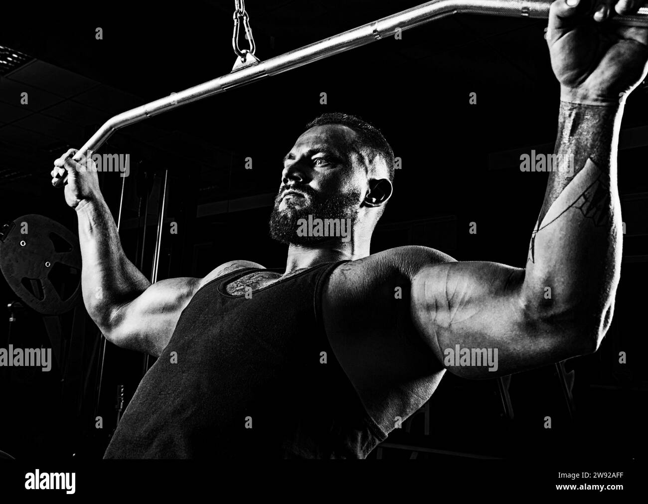 Professional athlete performs an exercise in the gym. Pulls the bar to