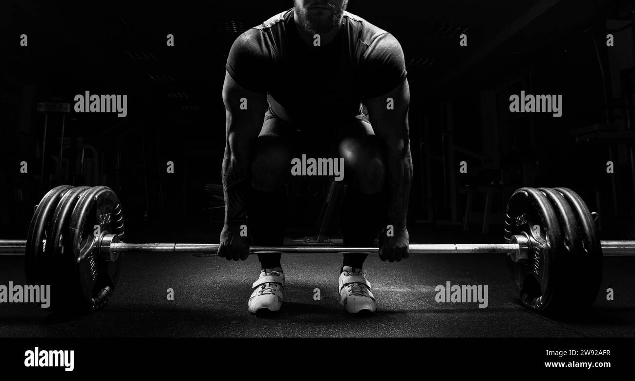 Huge man is preparing to perform an exercise called deadlift. Mixed media Stock Photo