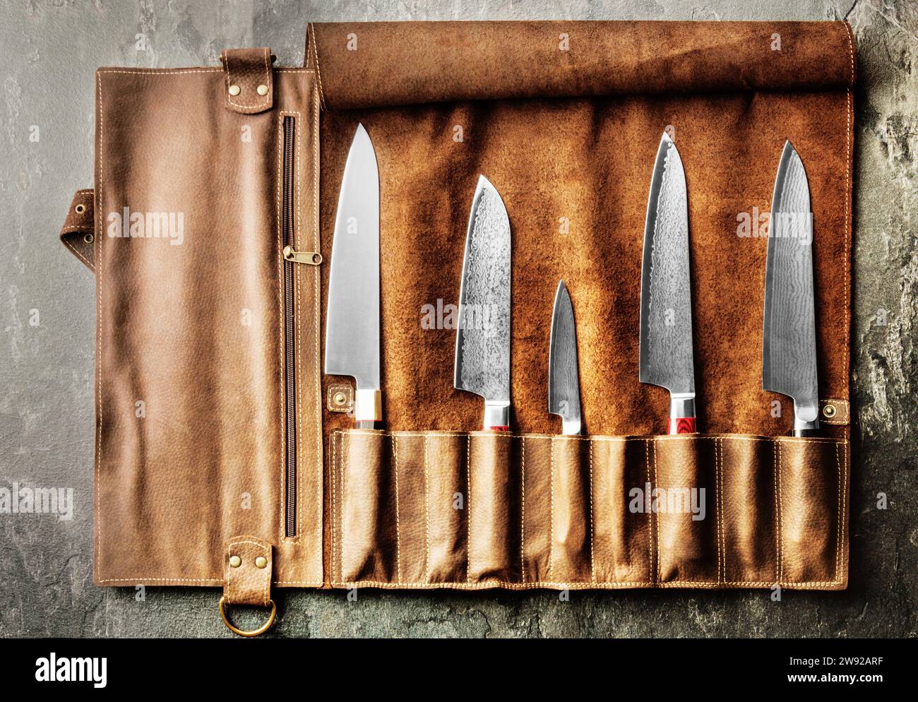 Japanese knives of different sizes from Damascus steel are in a leather case. Business concept of career growth Stock Photo
