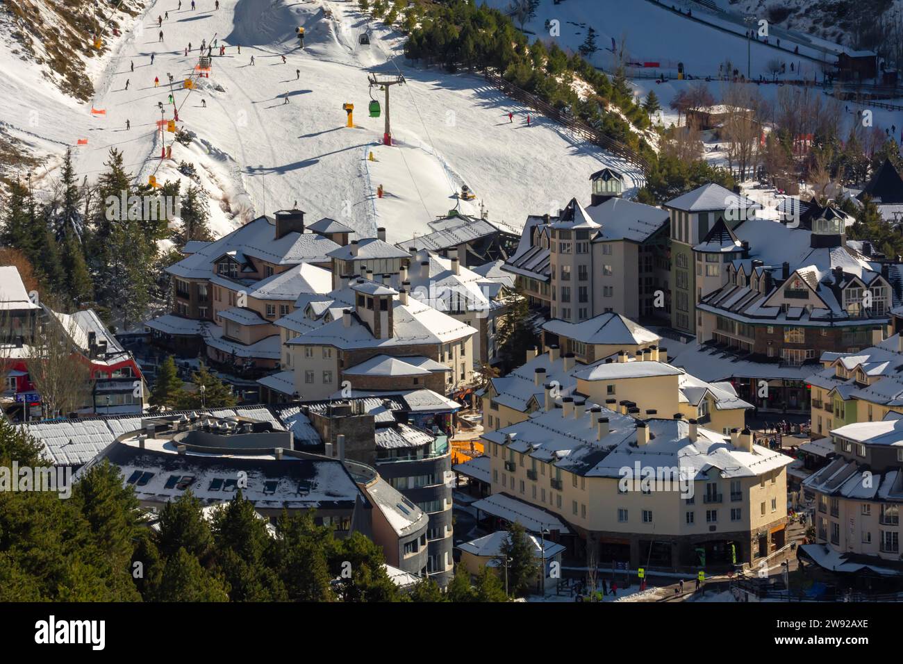 A mountain village nestled among snow-covered slopes with ski runs and alpine buildings Stock Photo
