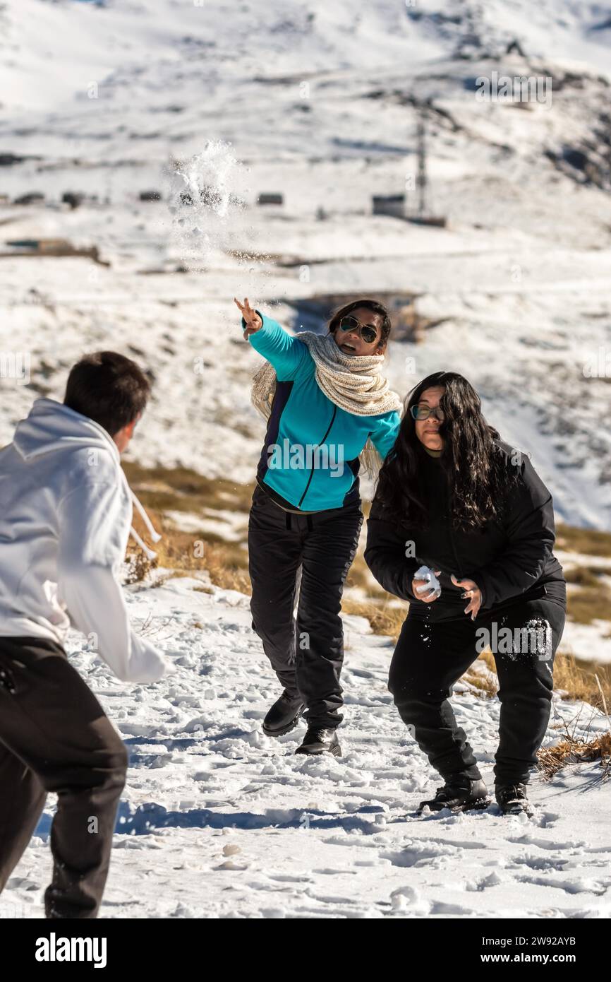 Latin family at ski resort, in granada sierra nevada having fun throwing snowballs, playing on a sunny day, andalucia, spain Stock Photo