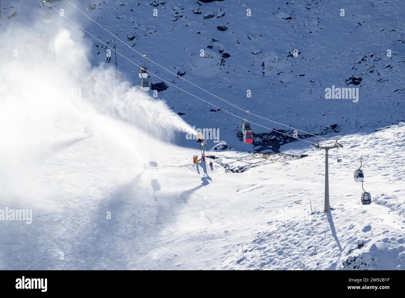 Snow cannons, spreading snow on the slopes next to the cable cars in sierra nevada ski resort Stock Photo