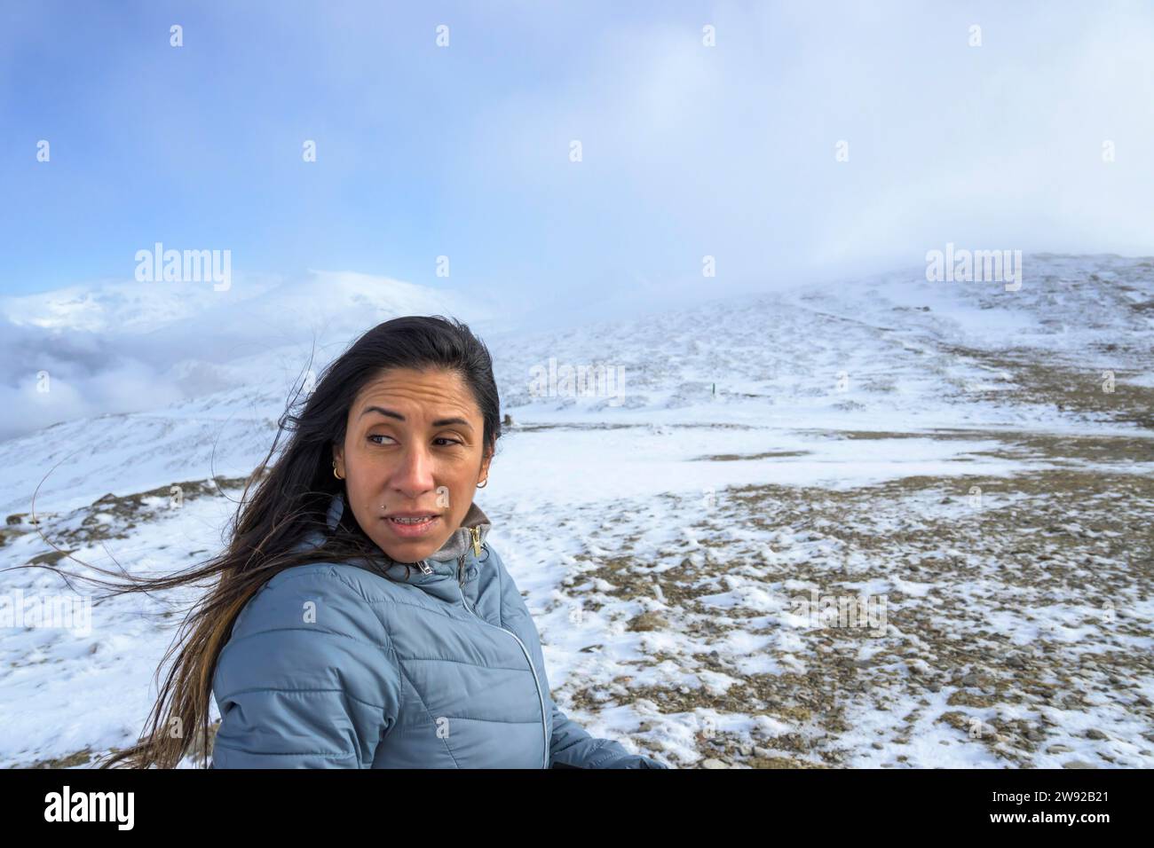Middle-aged latina woman on a snow-capped mountain in a blizzard Stock Photo