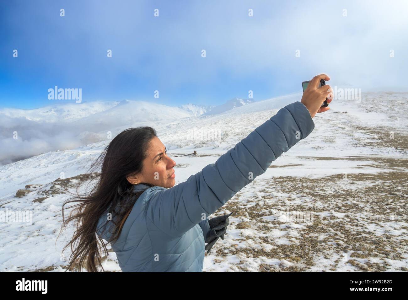 Latina woman taking a selfie with a smartphone while enjoying a winter day in sierra nevada, granada Stock Photo