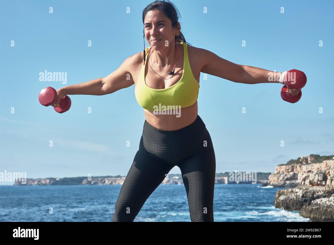Latin woman, middle-aged, wearing sportswear, training, doing physical exercises, plank, sit-ups, climber's step, burning calories, keeping fit Stock Photo